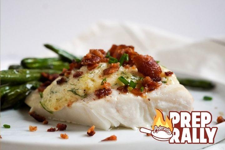 Closeup image of creamy bacon halibut sitting on a white plate with green beans in the background.