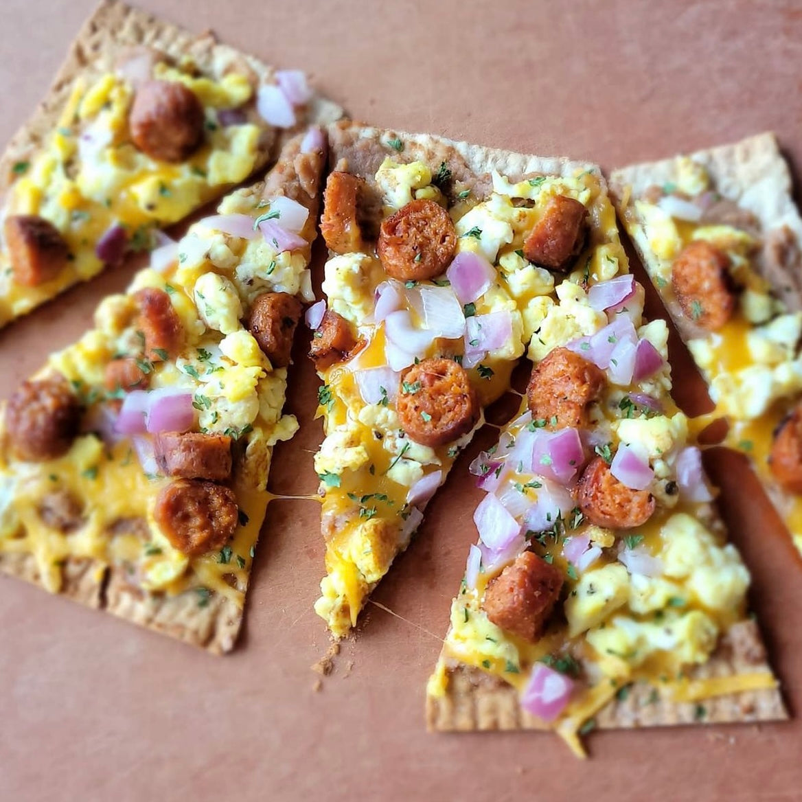 Five slices of thin crust pizza topped with cut up Spicy Breakfast Sausage Links, onions and cheese.