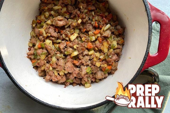 Image of cooked Paleo Sausage Stuffing sitting in a red dutch oven with an interior white coating.