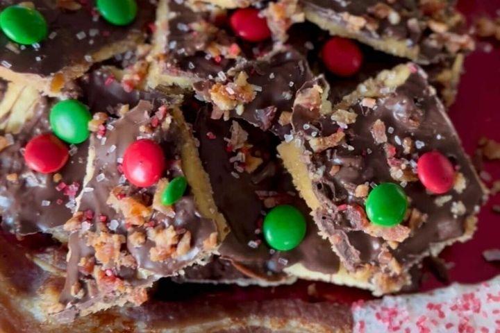 A pile of Sea Salt Bacon Toffee pieces topped with green and red M&Ms candy.